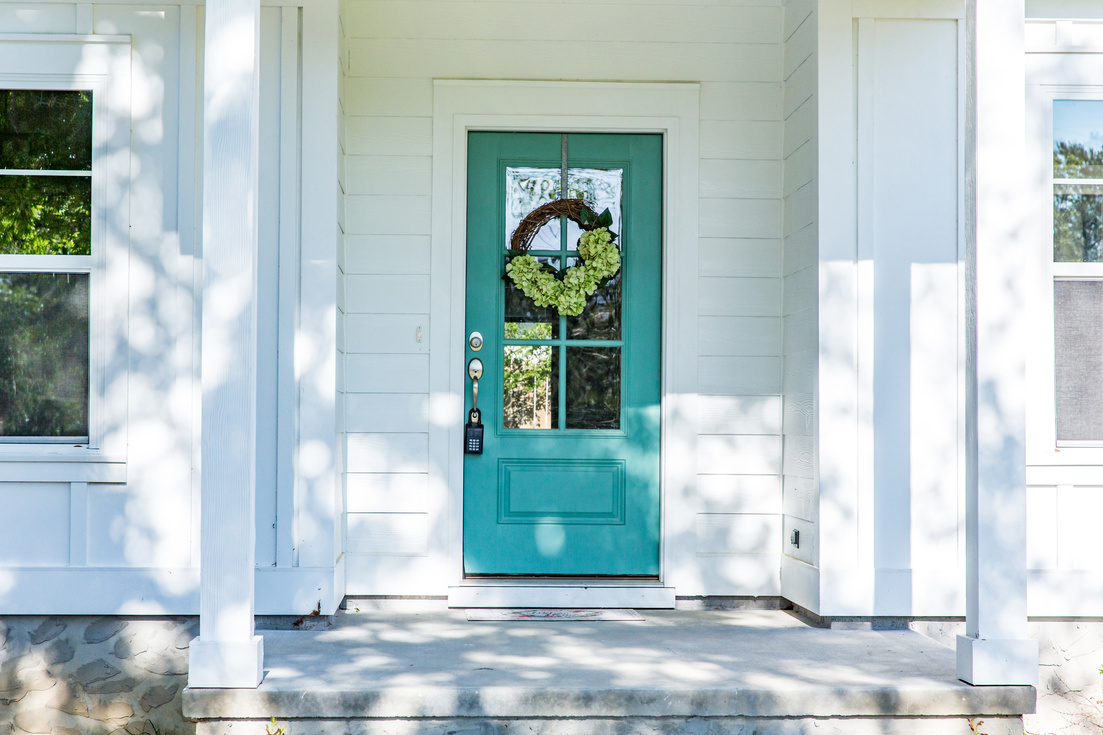 Exterior facade of a white new construction house with a turquoise front door